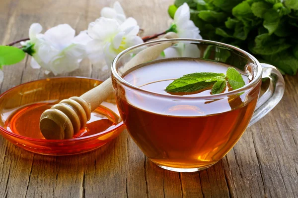 Tasse Tee mit Minze und Honig auf einem Holztisch — Stockfoto