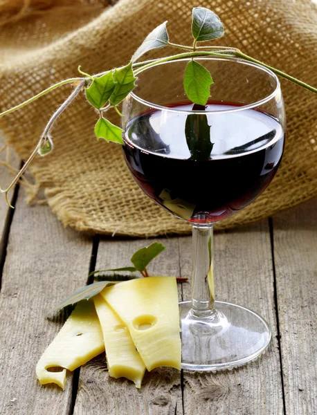 Glass av rødvin og ostebiter på et trebord – stockfoto