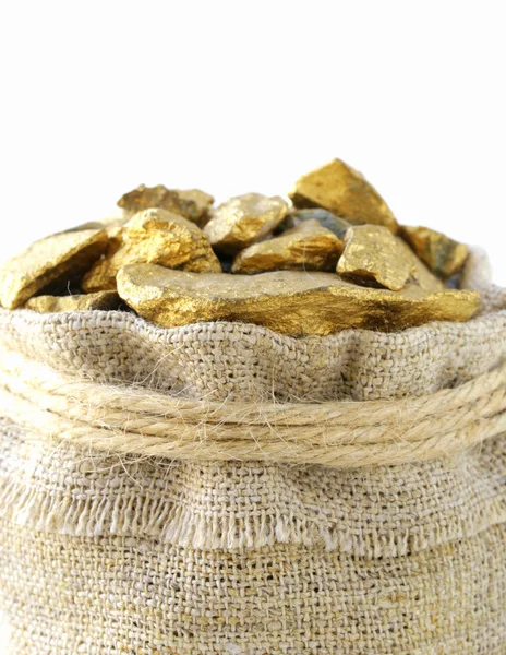 Pepitas de ouro em um saco de linho em um fundo branco — Fotografia de Stock