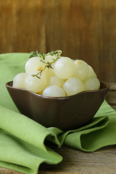 Piccole cipolle di perla messe sotto aceto su un tavolo di legno — Foto Stock