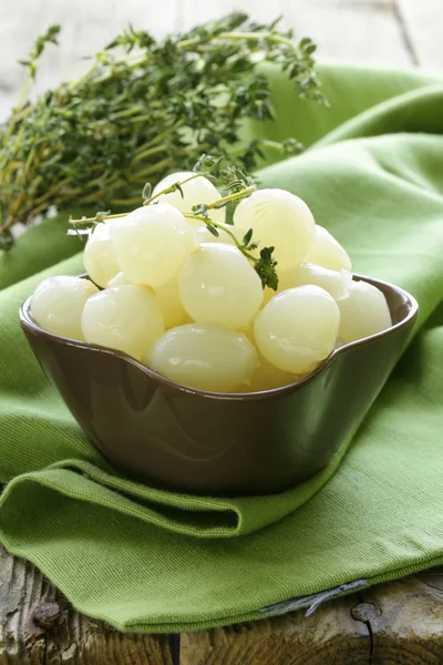 Kleine eingelegte Perlzwiebeln auf einem Holztisch — Stockfoto