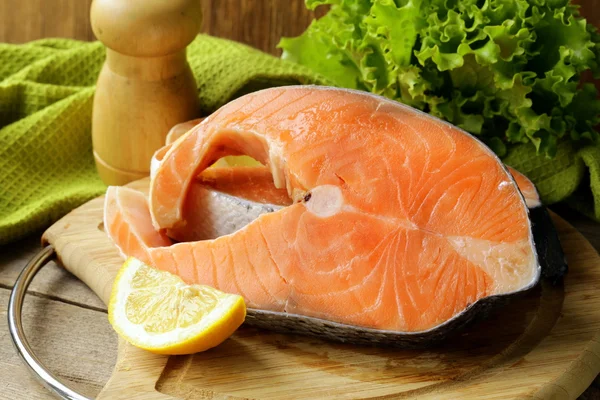 Pescado rojo crudo fresco (salmón) en una tabla de cortar — Foto de Stock