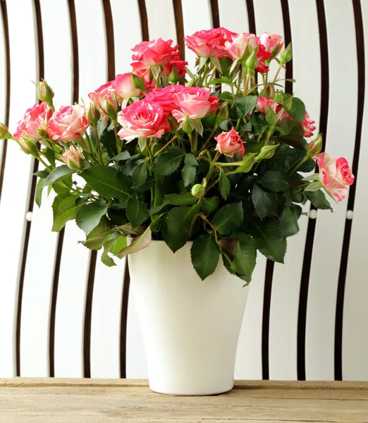 Цветы розы в вазе на деревянном фоне — стоковое фото