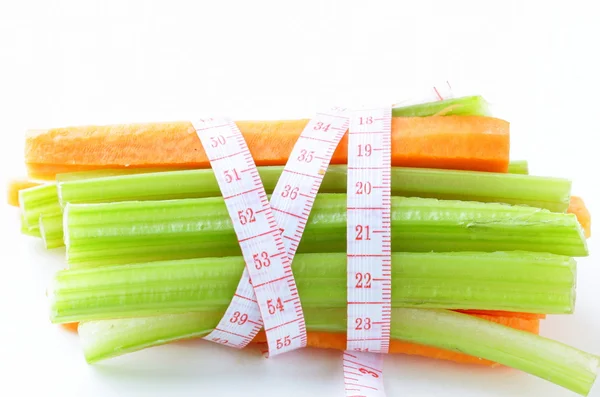 Zanahorias, apio verde, cinta métrica sobre un fondo blanco — Foto de Stock
