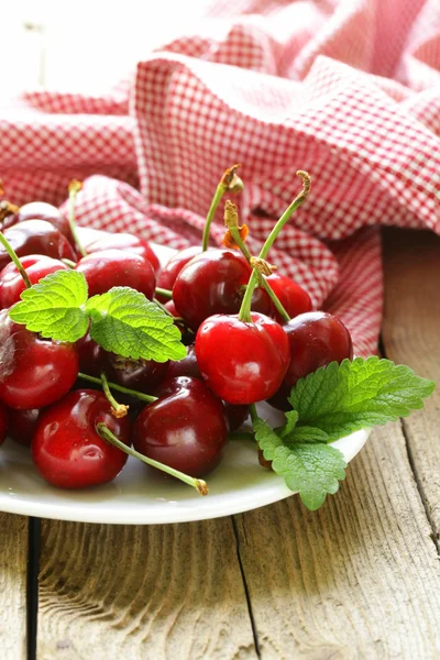 Cherry bessen met munt laat op een houten tafel — Stockfoto