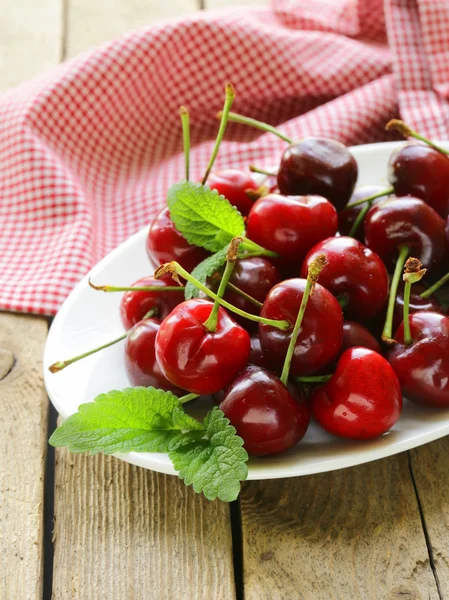 Cherry berries with mint leaves on a wooden table — Stock Photo, Image