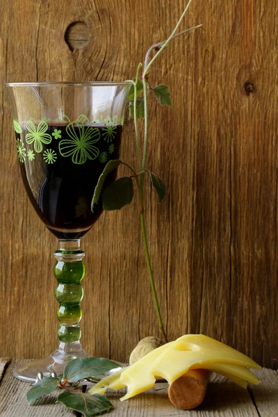 Glas Rotwein und Käsescheiben auf einem Holztisch — Stockfoto