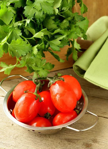 Tomates cherry húmedos frescos y manojo de perejil sobre la mesa —  Fotos de Stock