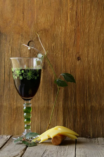 Pohár vörös bor és a sajt egy fából készült asztal szelet — Stock Fotó