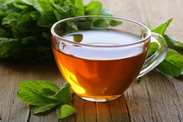 Tazza di tè con menta su un tavolo di legno — Foto Stock