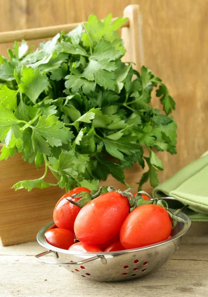 Frische feuchte Kirschtomaten und ein Bund Petersilie auf dem Tisch — Stockfoto