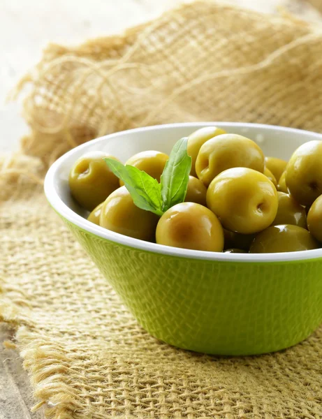 Groene gemarineerde olijven met kruiden op een houten tafel — Stockfoto