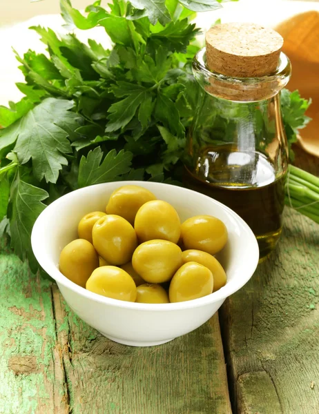 Yeşil zeytin ahşap bir masa üzerinde otlar ile marine edilmiş. — Stok fotoğraf