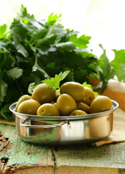 Yeşil zeytin ahşap bir masa üzerinde otlar ile marine edilmiş. — Stok fotoğraf