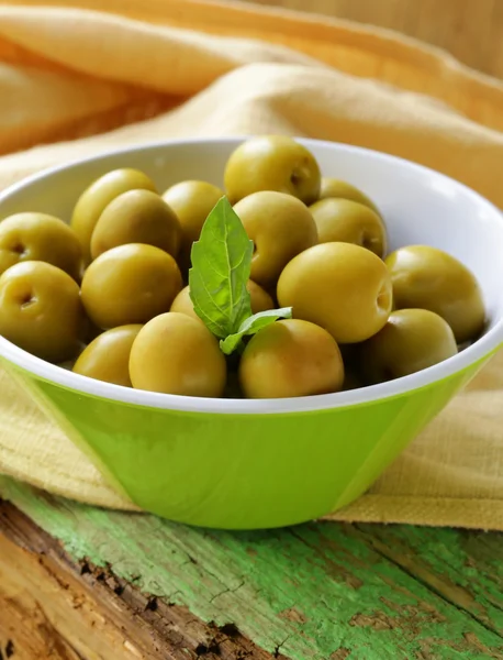 Groene gemarineerde olijven met kruiden op een houten tafel — Stockfoto