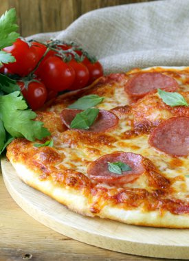 pepperoni pizza domates sosu ve ahşap oyun tahtası bitkiler