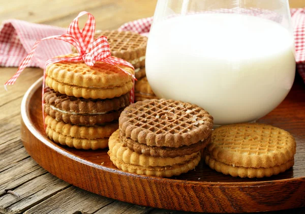 Biscoitos caseiros (sanduíche) com leite em uma mesa de madeira — Fotografia de Stock