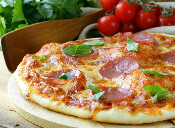 Pizza de pepperoni con salsa de tomate y hierbas en una tabla de madera —  Fotos de Stock