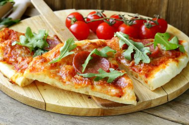 pepperoni pizza domates sosu ve ahşap oyun tahtası bitkiler