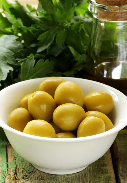 Yeşil zeytin ahşap bir masa üzerinde otlar ile marine edilmiş. — Stok fotoğraf