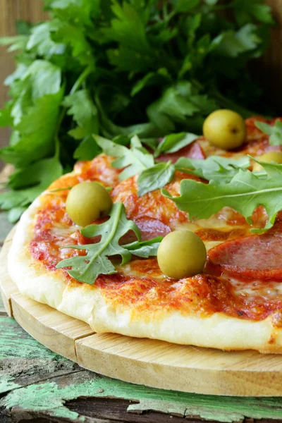 Pizza al salame piccante con salsa di pomodoro ed erbe aromatiche su una tavola di legno — Foto Stock