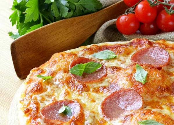 Pizza al salame piccante con salsa di pomodoro ed erbe aromatiche su una tavola di legno — Foto Stock