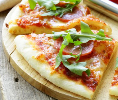 pepperoni pizza domates sosu ve ahşap oyun tahtası bitkiler