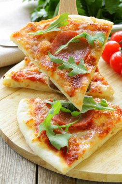 pepperoni pizza domates sosu ve ahşap oyun tahtası bitkiler