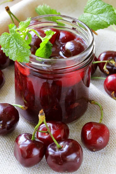 Cherry jam i en glasburk och mogna bär på bordet — Stockfoto