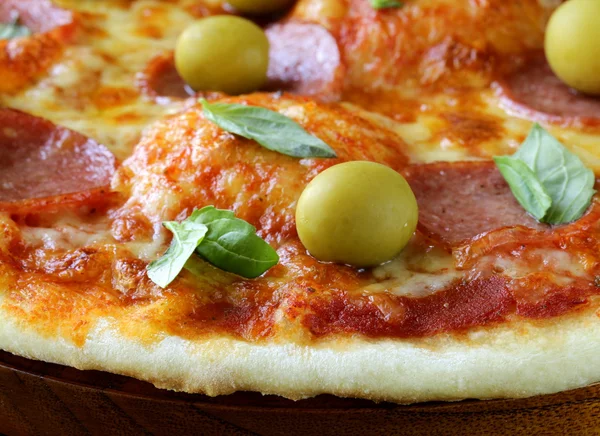 Pizza al salame piccante con salsa di pomodoro ed erbe aromatiche su una tavola di legno — Foto Stock