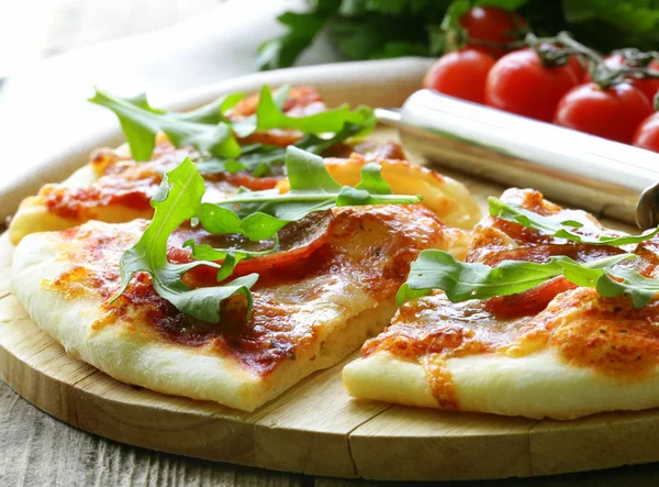 Pizza al salame piccante con salsa di pomodoro ed erbe aromatiche su una tavola di legno — Foto Stock