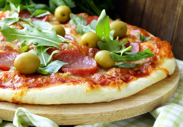 Pizza de pepperoni com molho de tomate e ervas em uma tábua de madeira — Fotografia de Stock
