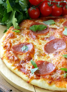 pepperoni pizza domates sosu ve ahşap oyun tahtası bitkiler
