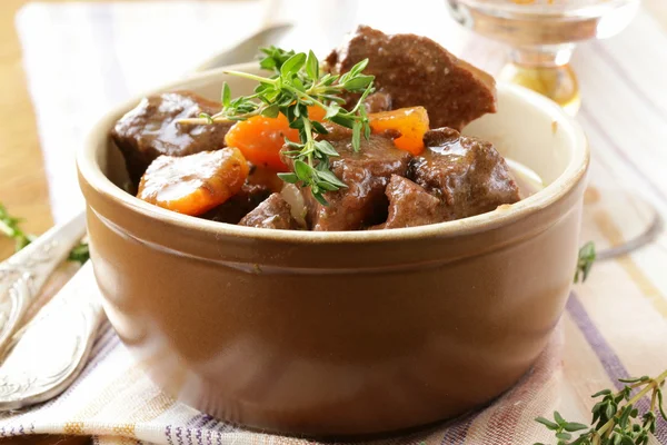 Beef goulash (stew) with vegetables and herbs on a wooden table — Stock Photo, Image