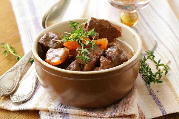 Rindergulasch (Eintopf) mit Gemüse und Kräutern auf einem Holztisch — Stockfoto