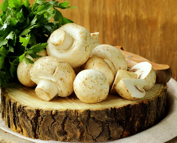 Cogumelos frescos (champinhons) em uma mesa de madeira — Fotografia de Stock