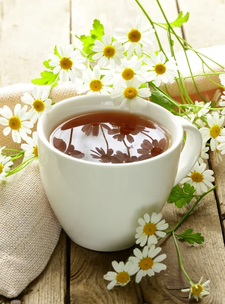 Taza de flores de té y manzanilla sobre una mesa de madera — Foto de Stock