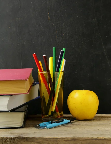 Papelaria (caneta, lápis, régua, bússola) e um livro sobre fundo placa escola preta — Fotografia de Stock