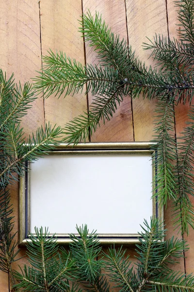 Christmas wooden background gold frame and fir tree branches — Stock Photo, Image