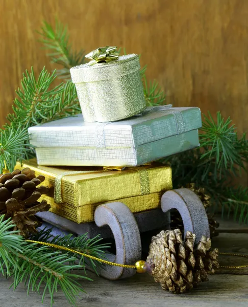 Weihnachtskomposition - ein Holzschlitten mit Geschenken und Tannenzweigen — Stockfoto