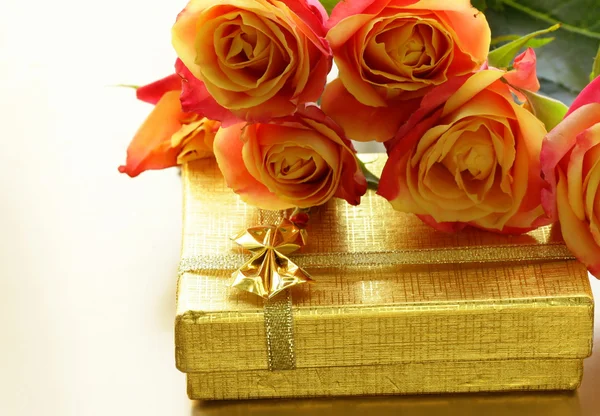 橙色玫瑰和黄金背景上的礼品包装盒 — 图库照片