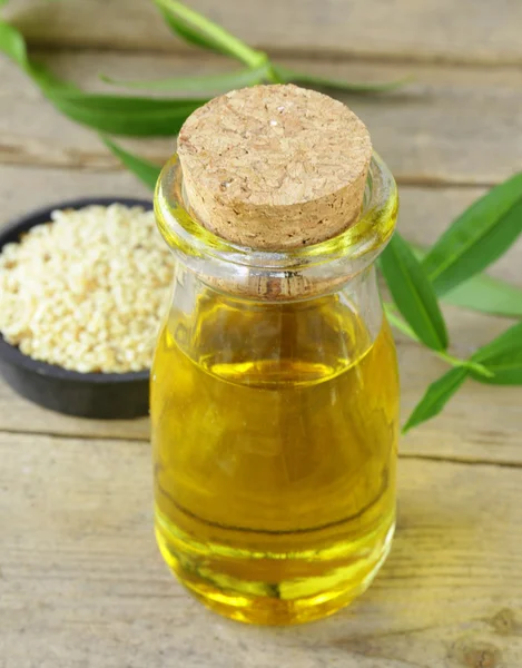 Семена кунжута и масло на деревянном столе — стоковое фото
