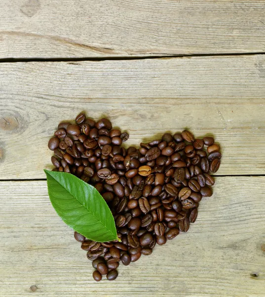 Кофейные зерна в форме сердца на деревянном фоне — стоковое фото