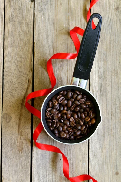 Grãos de café e cafeteira vermelha em uma mesa de madeira — Fotografia de Stock