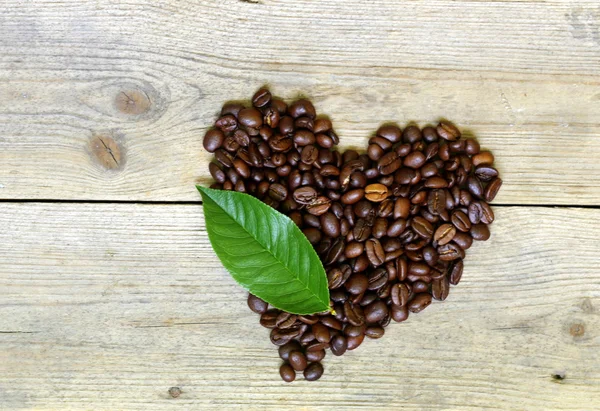 Kávová zrna v tvaru srdce na dřevěné pozadí — Stock fotografie