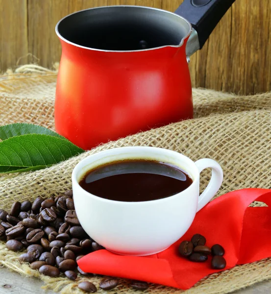 Koffiebonen en rode koffiepot op een houten tafel — Stockfoto