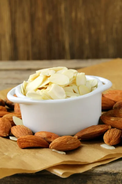 Whole nuts and blanched almonds in white bowl — ストック写真