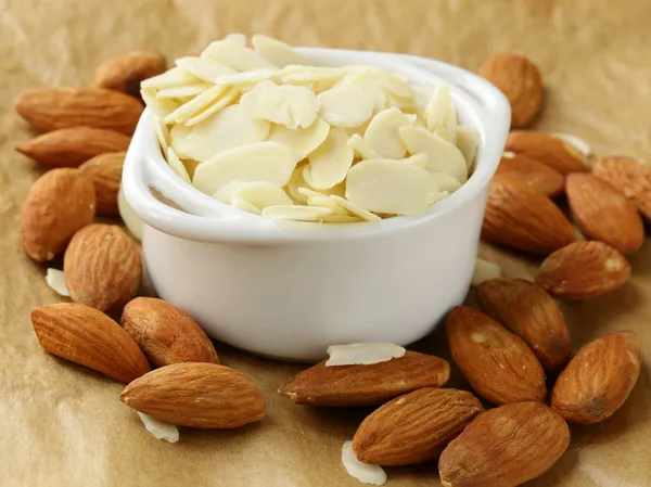 Whole nuts and blanched almonds in white bowl — Stock Photo, Image