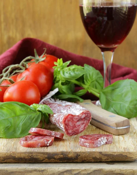 Stilleven van delicatesse salami, tomaten en basilicum - rustieke stijl — Stockfoto