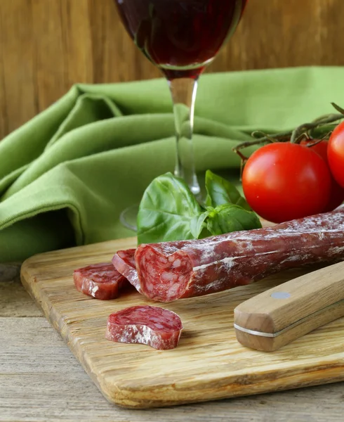 Still life of delicacy salami, tomatoes and basil - rustic style — Stock Photo, Image
